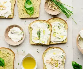 Tostas de pan de albahaca, queso a las hierbas con piñones y aceite de limón
