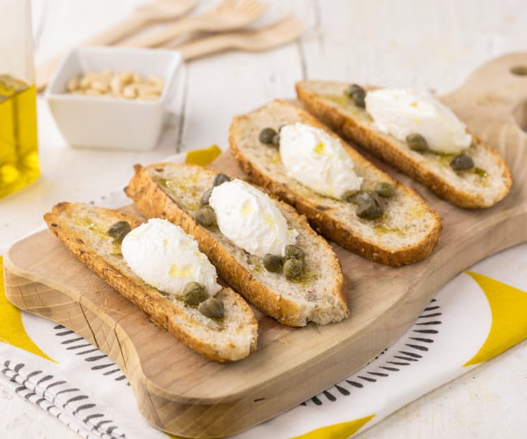 Crostini di pane integrale con crema al caprino, capperi e pinoli