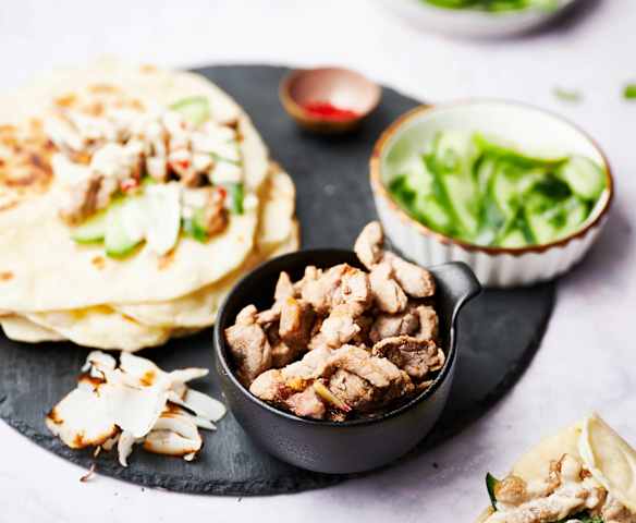 Solomillo de cerdo con salsa de coco picante, pan de ajo naan y ensalada de pepino